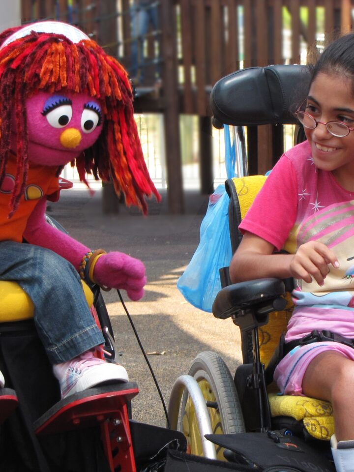 The Israeli muppet, Sivan, plays with a girl who also uses a wheelchair in Friendship Park.