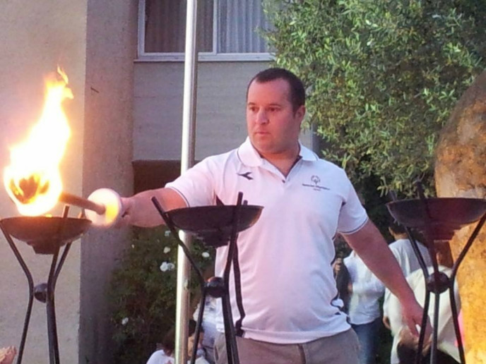 Special Olympics swimming champ Mati Oren lighting an Independence Day torch at Kibbutz Ginegar on April 23, 2015.
