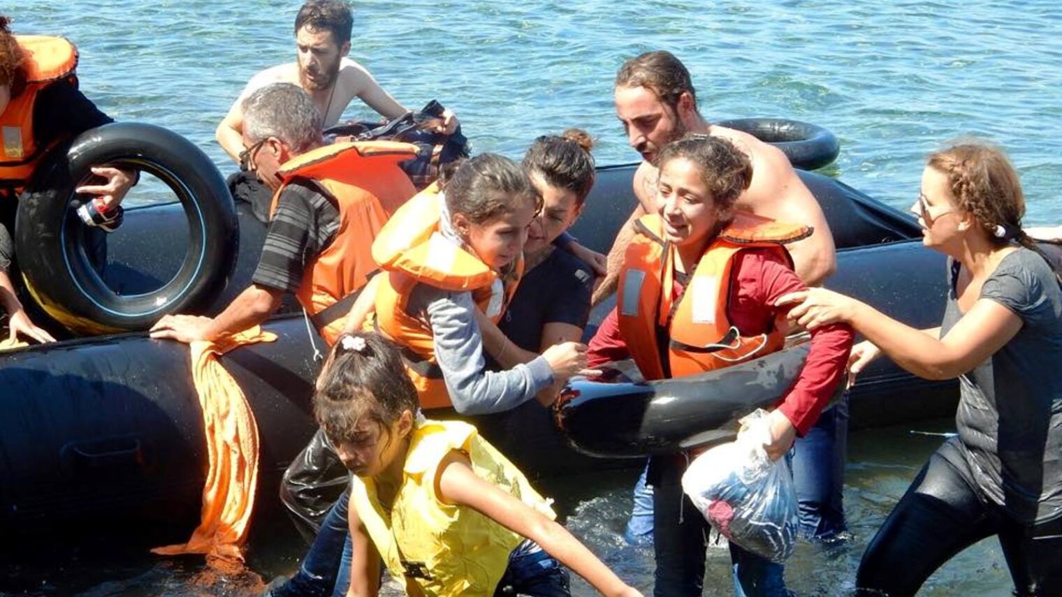 IsraAid volunteers including Naama Gorodischer, center, helping refugees reach the shore after their boat overturned off the Greek coast, September 13, 2015. Photo via Facebook
