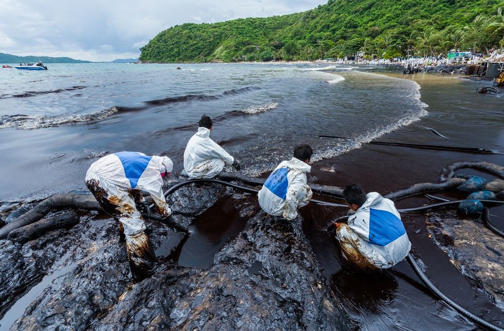 Workers in biohazard suits clean up an oil spill on Ao Prao Beach in Rayong, Thailand in July 2013.  Photo by Narongsak Nagadhana/Shutterstock.com
