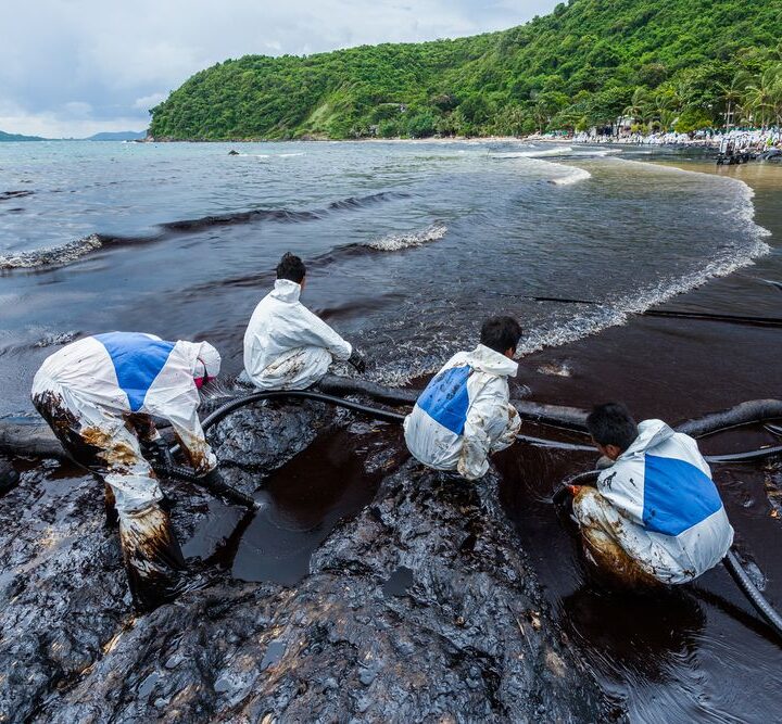 Workers in biohazard suits clean up an oil spill on Ao Prao Beach in Rayong, Thailand in July 2013.  Photo by Narongsak Nagadhana/Shutterstock.com