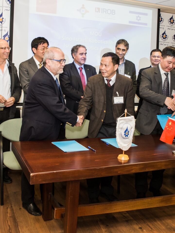 Israeli Robotics Association President Prof. Zvi Shiller, left, at table, shaking hands with officials from China at the MoU signing. Photo by Yair Golov