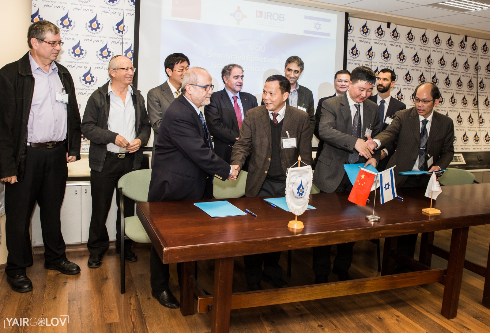 Israeli Robotics Association President Prof. Zvi Shiller, left, at table, shaking hands with officials from China at the MoU signing. Photo by Yair Golov