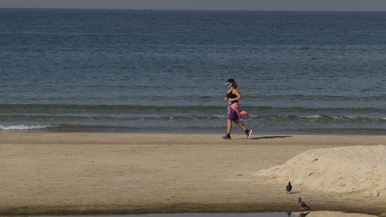A woman jogs along the beach in Herzliya. Exercise is one of the key ways to reduce sugar levels in the blood. Photo by Flash90