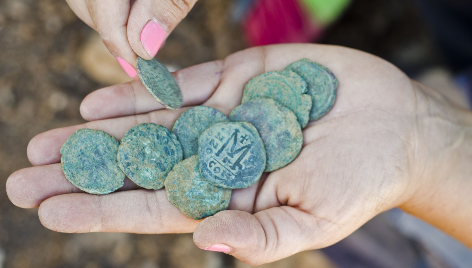 The cache of Byzantine coins in the hands of Annette Landes-Nager, excavation director on behalf of the Israel Antiquities Authority. Photo by Yoli Shwartz/IAA