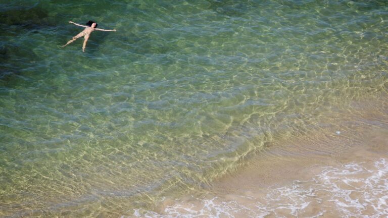 A woman enjoys a quiet dip in the sea on a beach in Tel Aviv. Photo by Miriam Alster/FLASH90