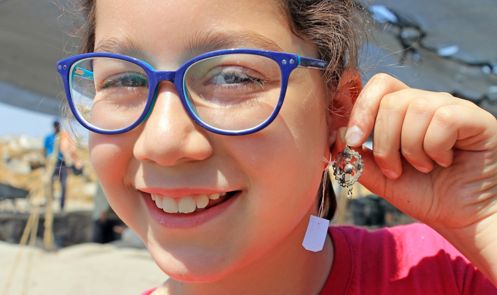 A young volunteer digger showing off the ancient earring she found at Givat Tittora. Photo by Vered Bosidan/Israel Antiquities Authority