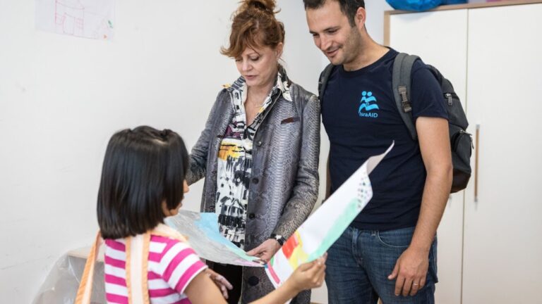 Susan Sarandon and IsraAID co-CEO Yotam Polizer with a child in one of IsraAID’s art therapy sessions in a German refugee camp. Photo by Boaz Arad