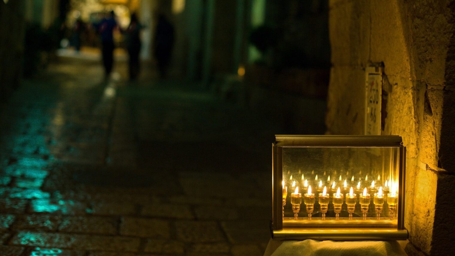 A main street through the Jewish Quarter of Jerusalem’s Old City, where a single menorah burns brightly on the eighth night of Hanukkah. Photo by Yehoshua Halevi