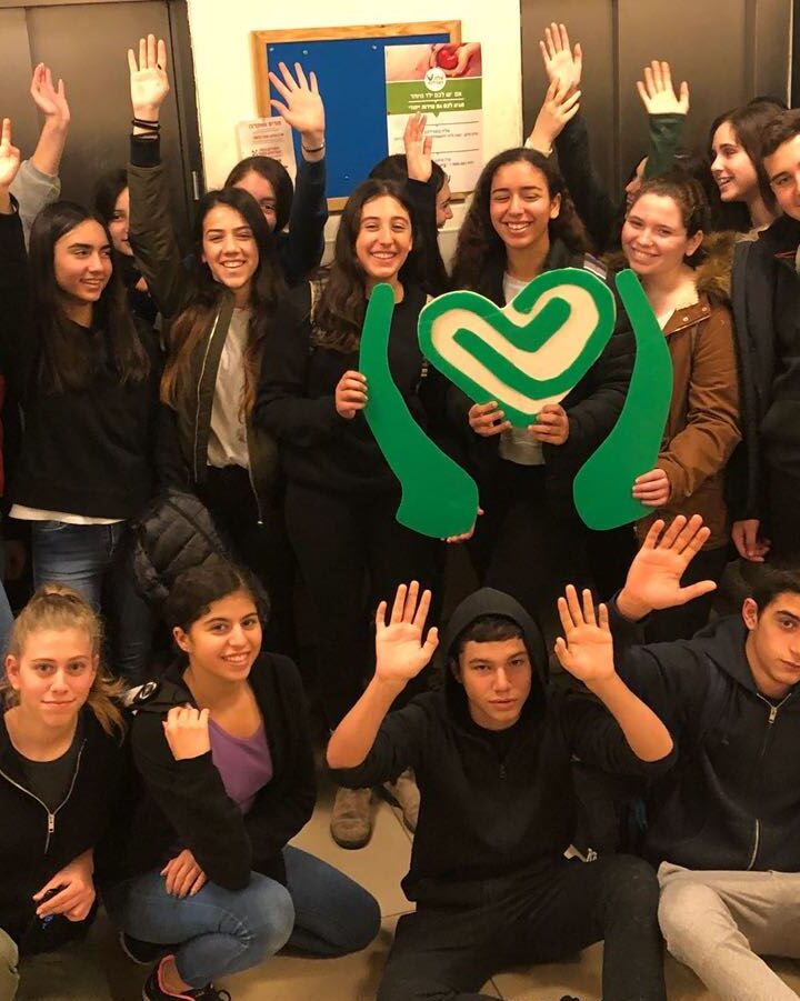 Ninth-graders from Modii’n pose with the Tikkun Olam logo during a visit to ALEH Jerusalem. Photo courtesy of ALEH
