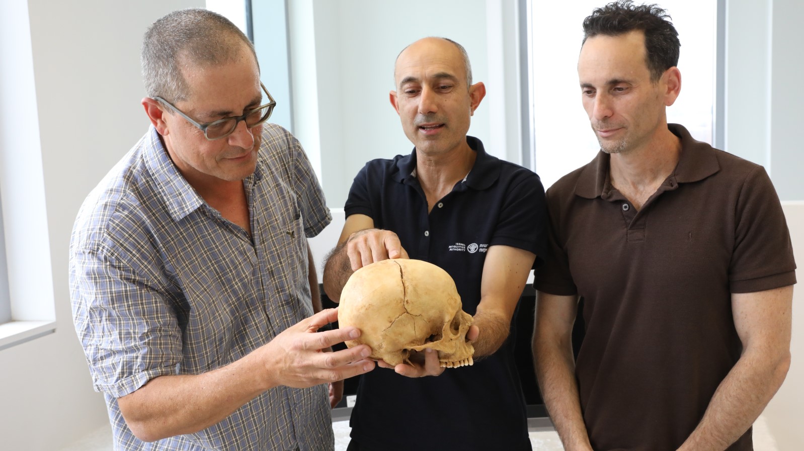 From left, Prof. Boaz Zissu, anthropologist Yossi Nagar and Dr. Haim Cohen of the National Center for Forensic Medicine with the 1,000-year-old skull. Photo by Chen Galili/IAA