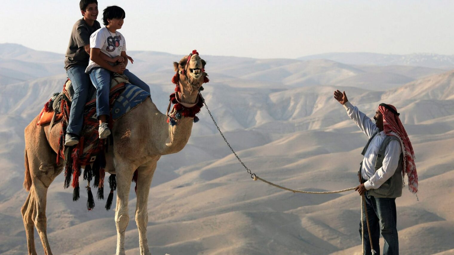 Young Israelis ride on a camel in the Judean desert. Photo by Nati Shohat/FLASH90