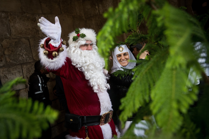 A man dressed as Santa Claus hands out Christmas trees in Jerusalem. Photo by Yonatan Sindel/Flash90