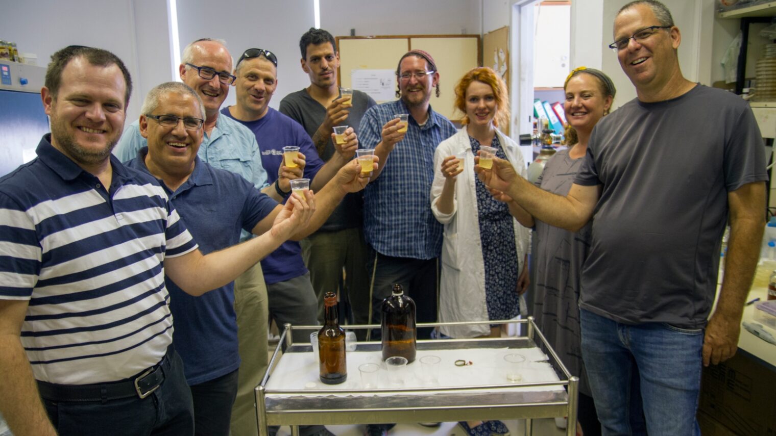 The team of Israeli researchers with new-old beer produced from ancient yeast. Photo by Yaniv Berman/Israel Antiquities Authority