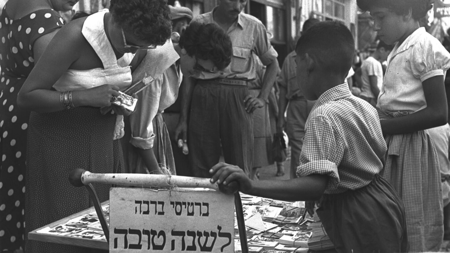 Israelis crowd around a temporary sidewalk tabletop stand in 1955 to purchase greeting cards for the Jewish New Year. Photo courtesy of the Government Press Office