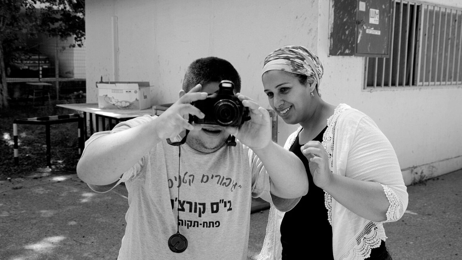 A volunteer facilitator teaches a PHOTO IS:RAEL participant how to document his own world. Photo by Carmella Keet