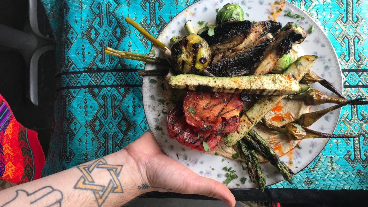 Chef Tal Caspi of Aviv PDX with a plate of hummus topped by grilled veggies. Photo: courtesy