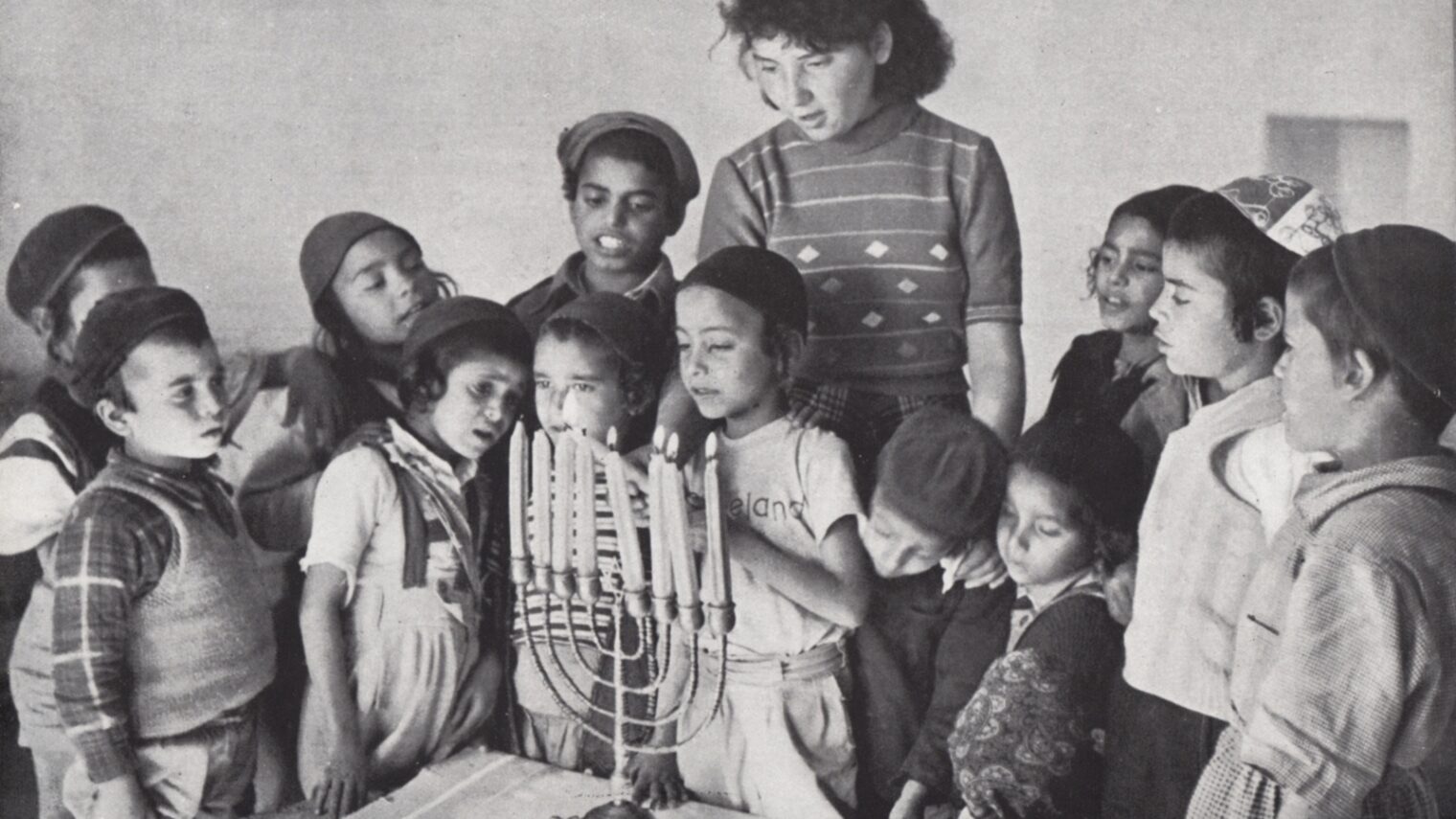 Schoolchildren light Hanukkah candles at a 1950s maabara immigrant camp. Photo: PikiWiki Israel