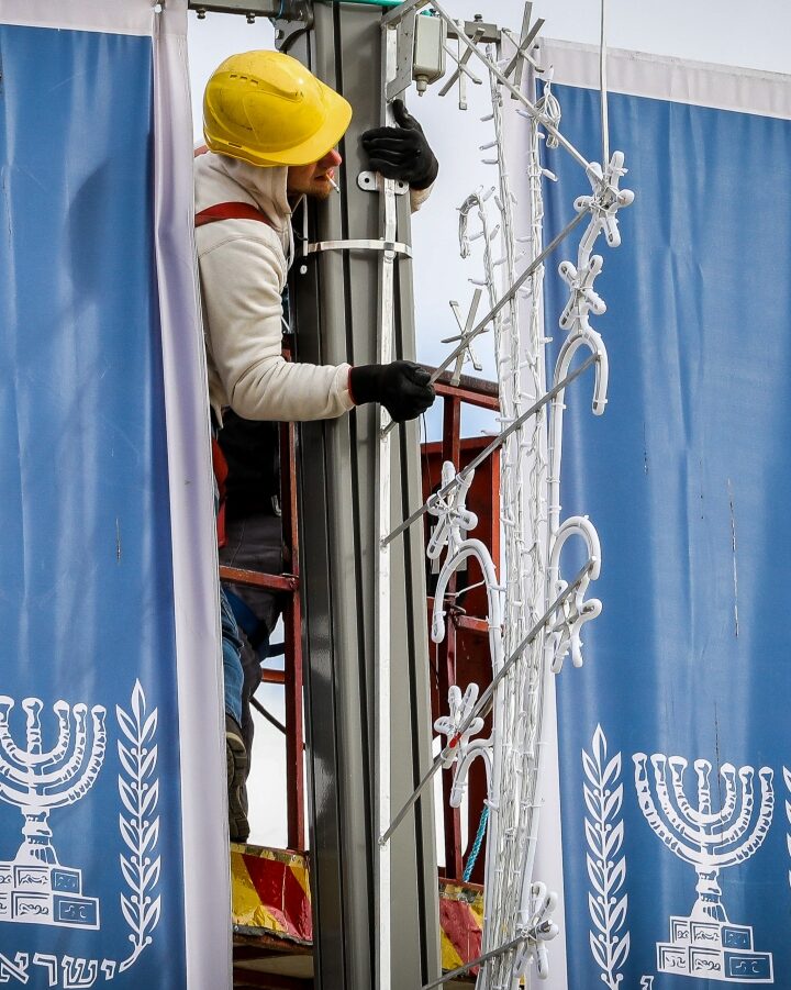 A worker hangs banners and lights near the President’s Residence in Jerusalem ahead of a visit from heads of state as part of the Fifth World Holocaust Forum. Photo by Yonatan Sindel/FLASH90