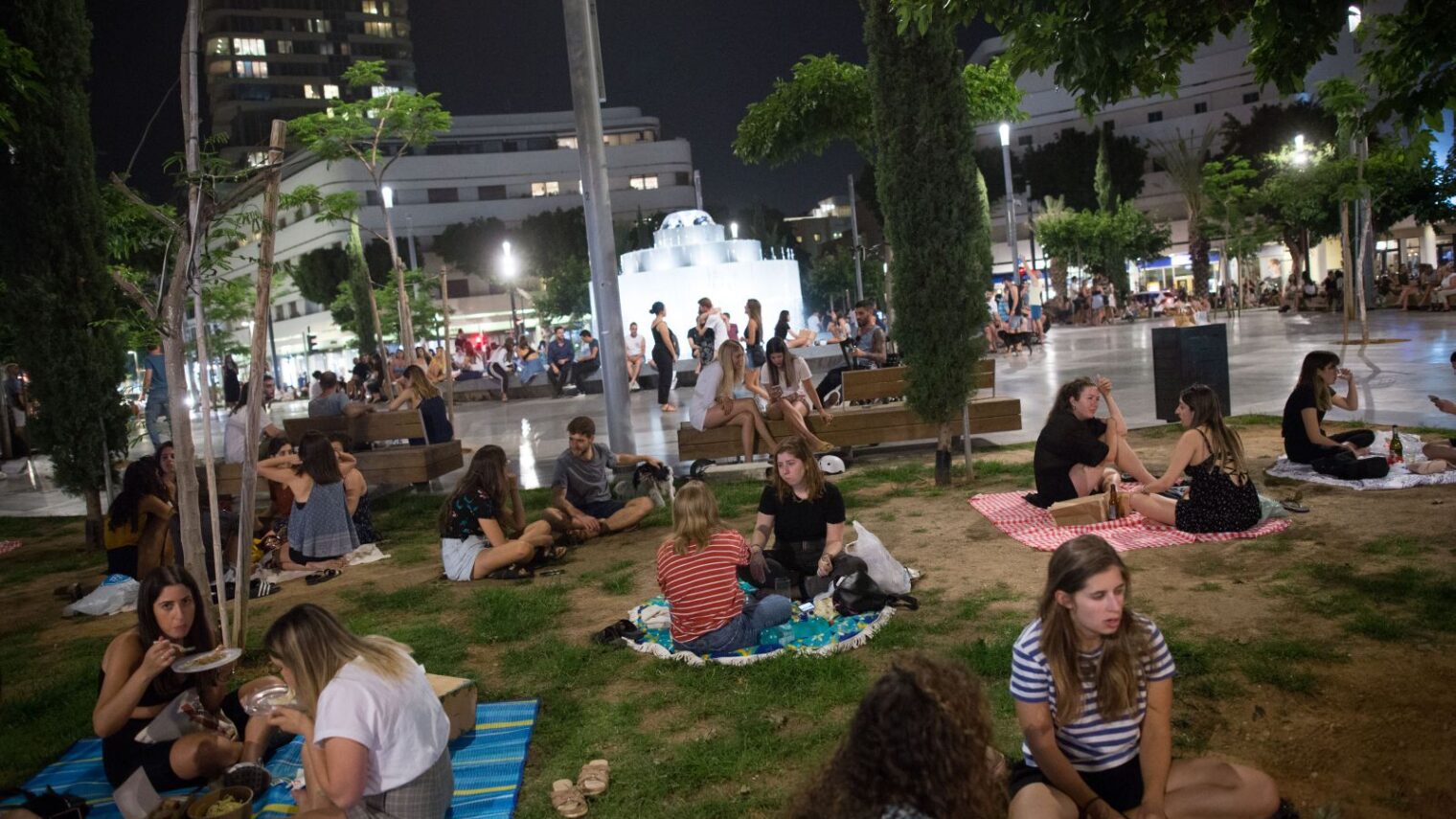 With bars and restaurants still closed, Israelis picnic in Dizengoff Square in Tel Aviv on May 20, 2020. An extreme heatwave meant facemasks were not obligatory. They are now mandatory again. Photo by Miriam Alster/Flash90