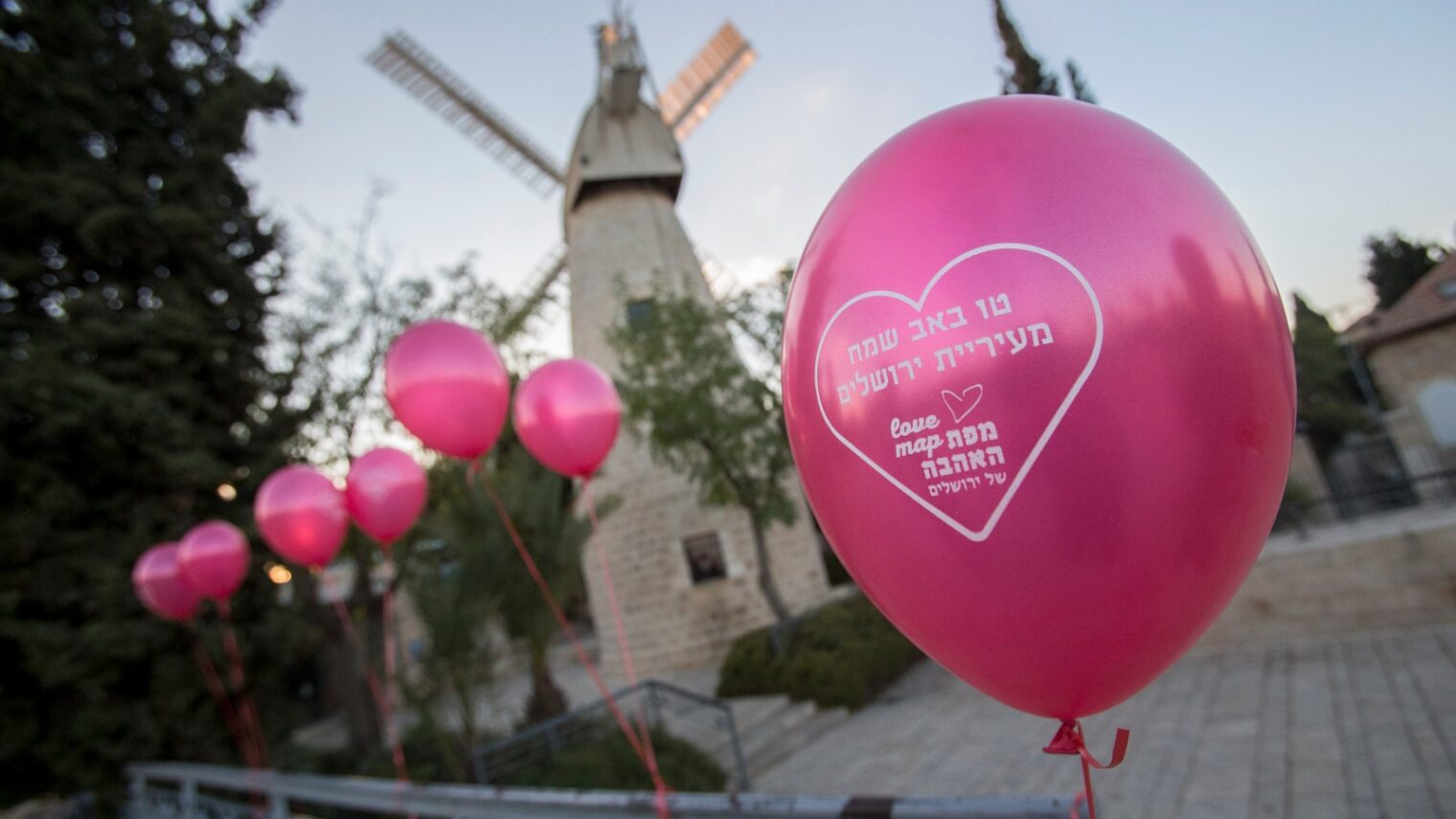 Balloons inscribed “Happy Tu B'Av from the Jerusalem Municipality” blow in the breeze near the Montefiore Windmill. Photo by Yonatan Sindel/Flash90