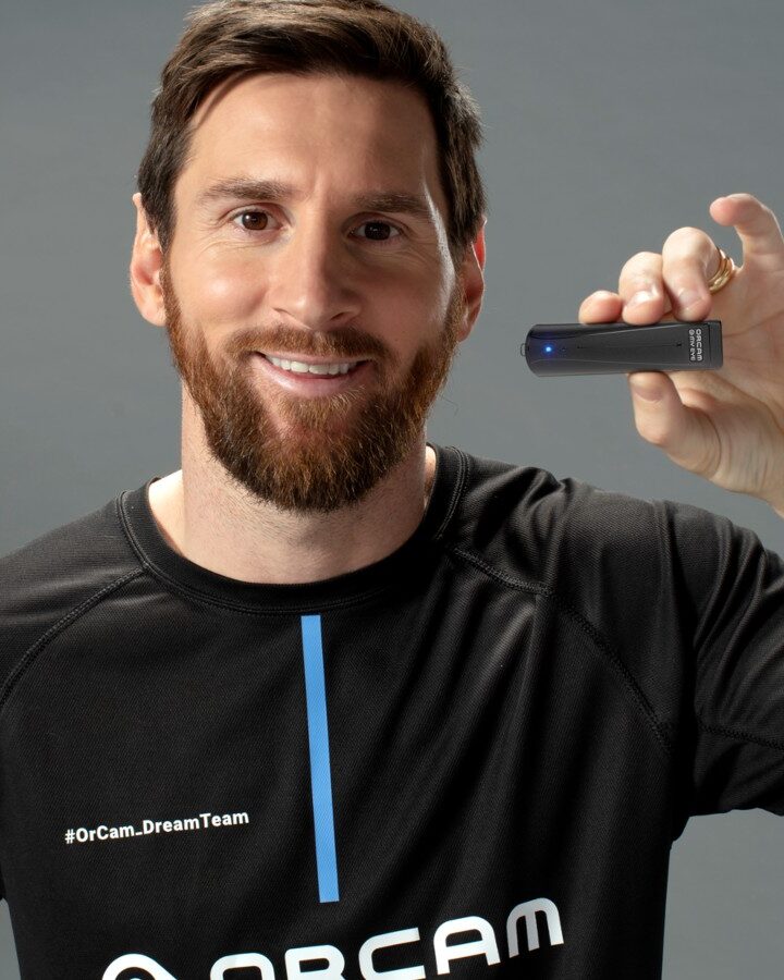 Lionel Messi holding the OrCam MyEye wearable device that reads text aloud. Photo courtesy of OrCam