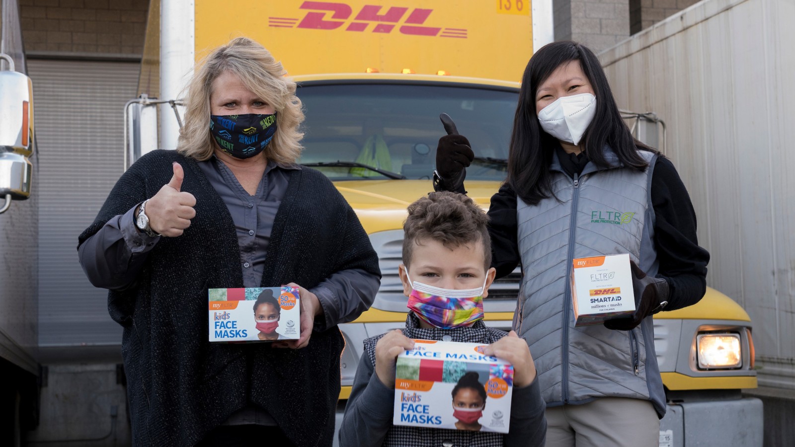 Mayor Dana Ralph of Kent, Washington, left, and SmartAID volunteer Trang Le handing the first box of donated masks to a local boy, kicking off the Millions of Masks for Children initiative. Photo by Paul Christian Gordon/SmartAID