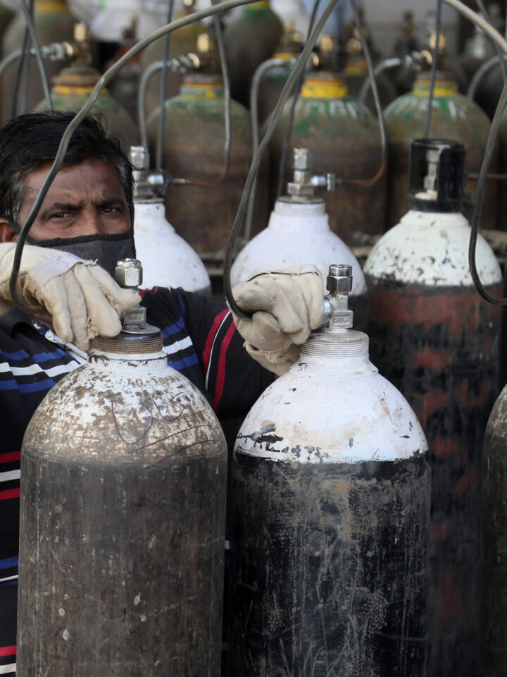 With oxygen in short supply in India, a worker refills medical oxygen cannisters for treatment of Covid-19 patients in New Delhi. Photo by Shutterstock