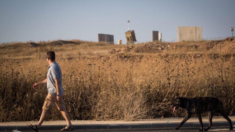 A man walks his dog next to an Iron Dome anti-missile battery near the city of Sderot in southern Israel. Photo by Yonatan Sindel/Flash90