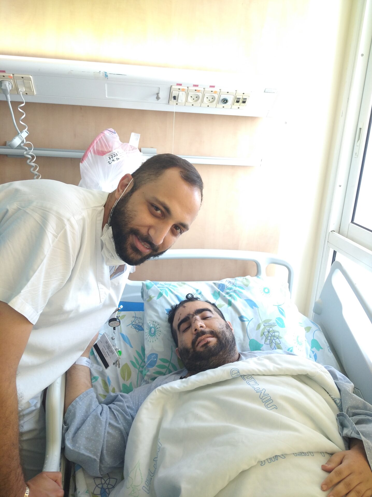 Fadi Kasem and Mor Janashvili (in the hospital bed) at an emotional reunion at the Galilee Medical Center in Nahariya. Photo courtesy Galilee Medical Center
