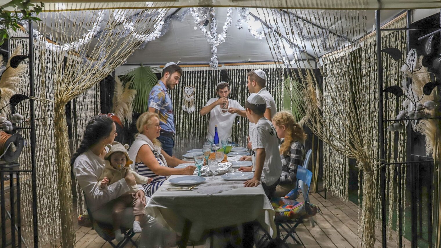 An Israeli family sitting in a sukkah during the Jewish holiday of Sukkot. Photo by Yossi Aloni/Flash90