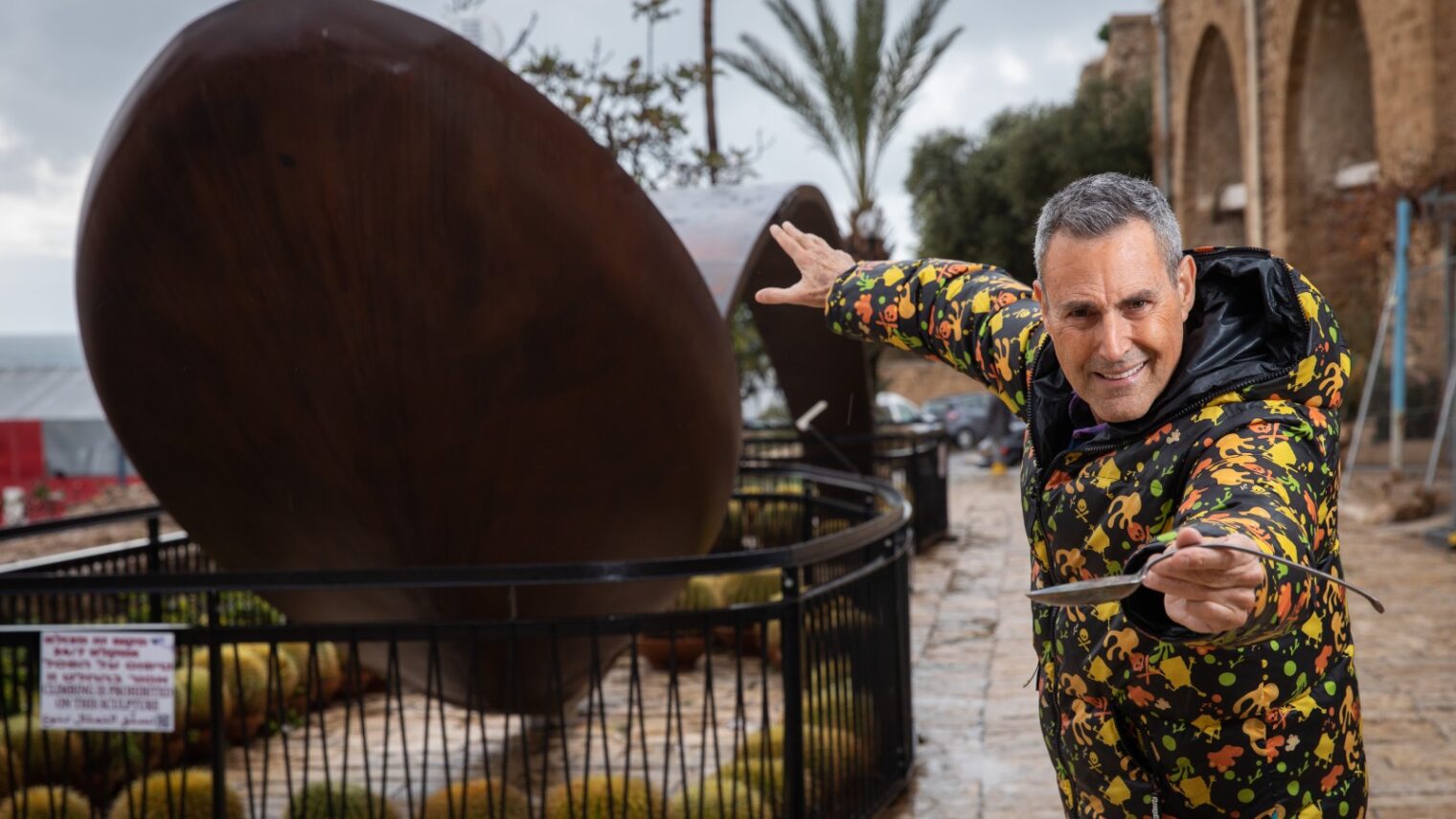 Mystifier Uri Geller next to a giant bent spoon outside his museum in Jaffa. Photo by Hadas Parush/Flash90