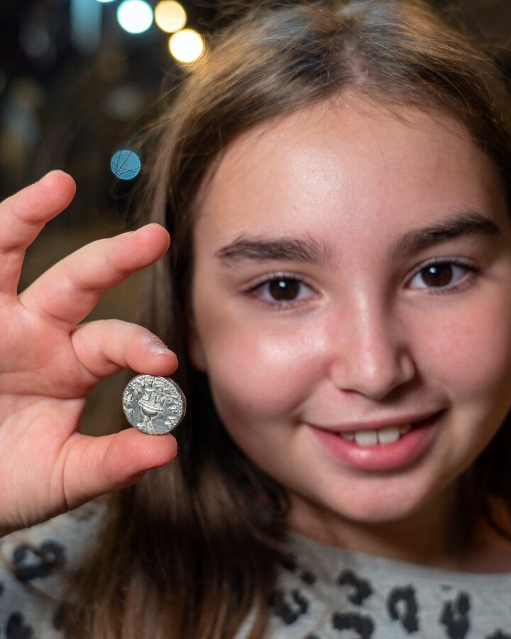 Liel Krutokop, 11, with the 2,000-year-old coin she found. Photo by Yaniv Berman/City of David and Israel Antiquities Authority