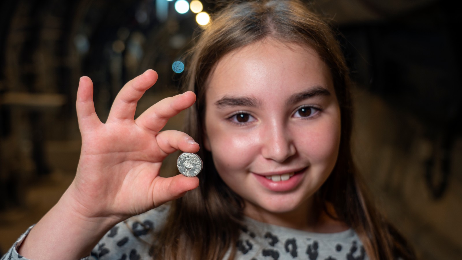 Liel Krutokop, 11, with the 2,000-year-old coin she found. Photo by Yaniv Berman/City of David and Israel Antiquities Authority
