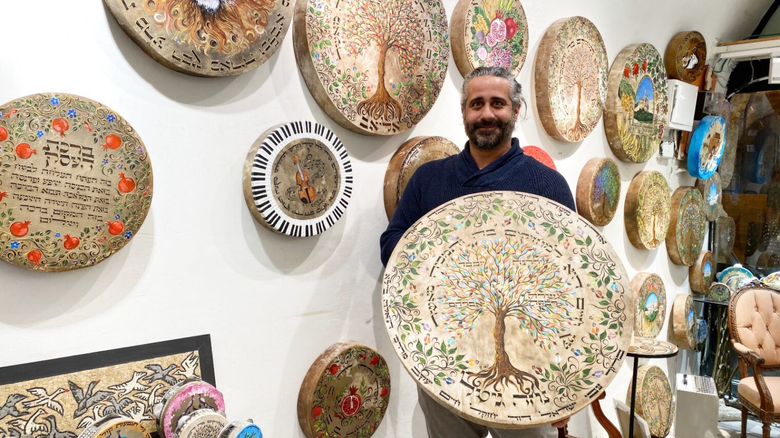 Rina gallery’s Chanan Eliav with parchment-on-wood paintings. Photo by Abigail Klein Leichman