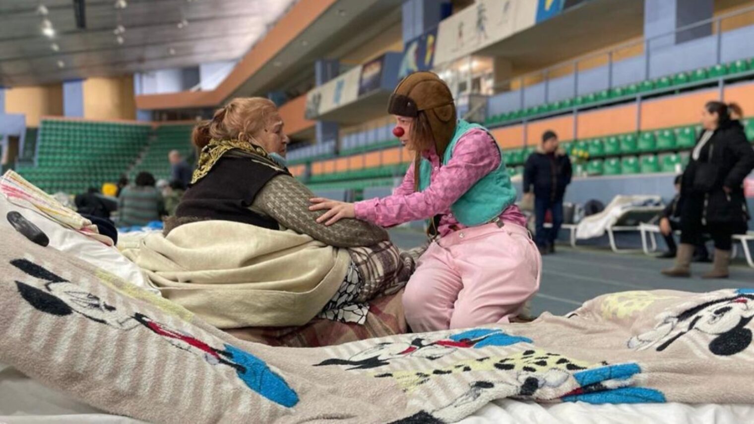 An Israeli medical clown comforting a displaced Ukrainian sheltering in a Moldovan stadium. Photo courtesy of Dream Doctors