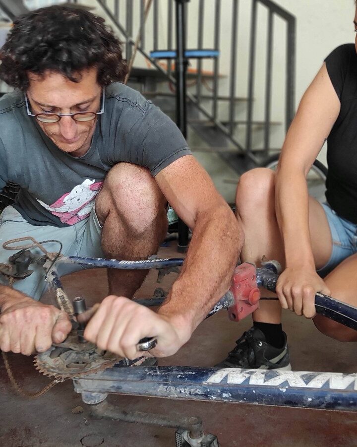 Nathanael Singer showing workshop visitors how to fix a bicycle. Photo courtesy of Pnimeet