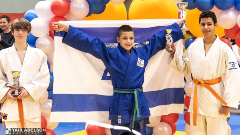 Nir Abelson, center, with this prize and the Israeli flag at the international judo contest in the Netherlands earlier this month.
