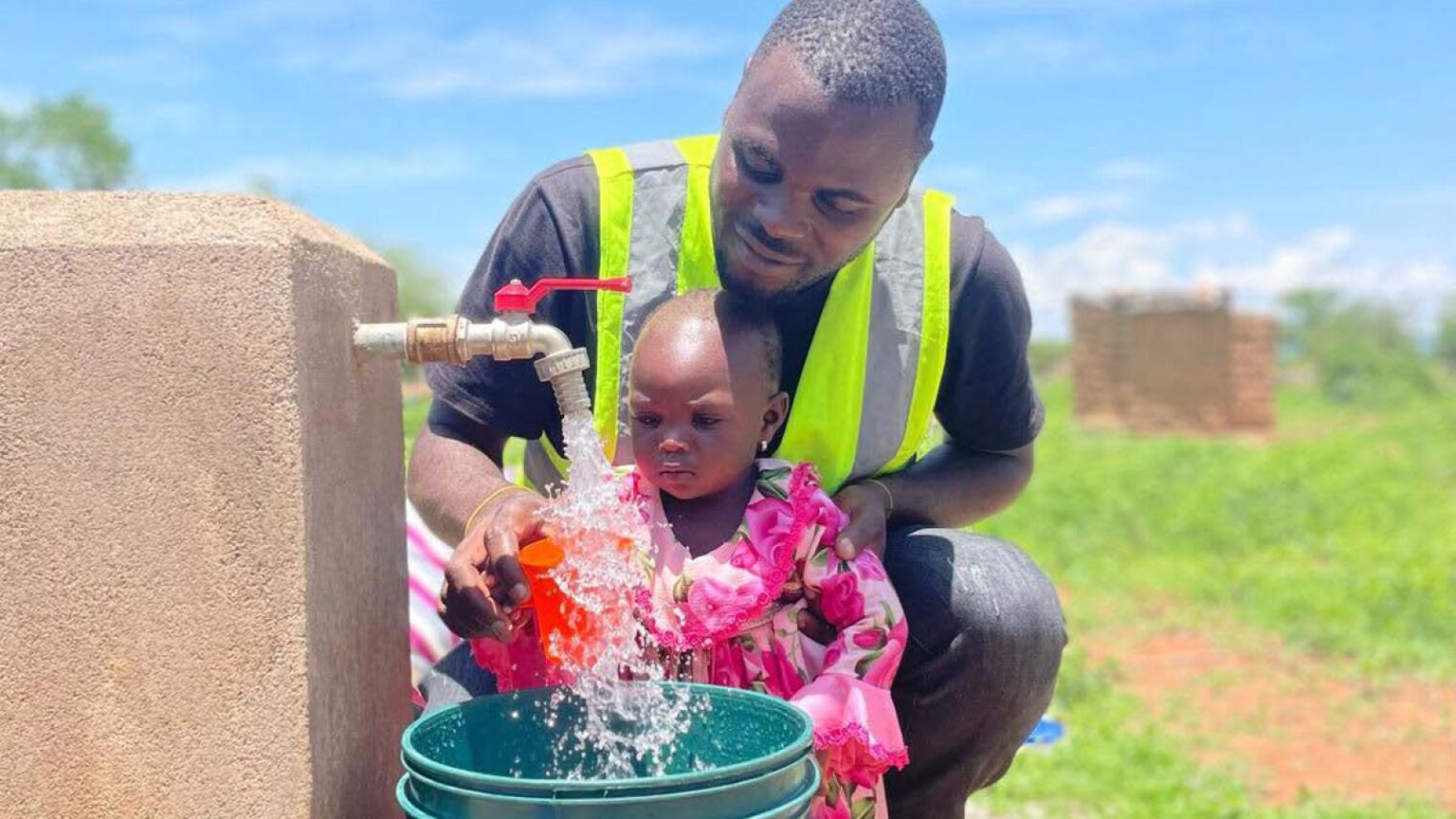Richard Dickson, a field hydrogeologist for Innovation: Africa in Tanzania, introducing a child to the wonders of running water in Mkoka Village. Photo courtesy of Innovation: Africa