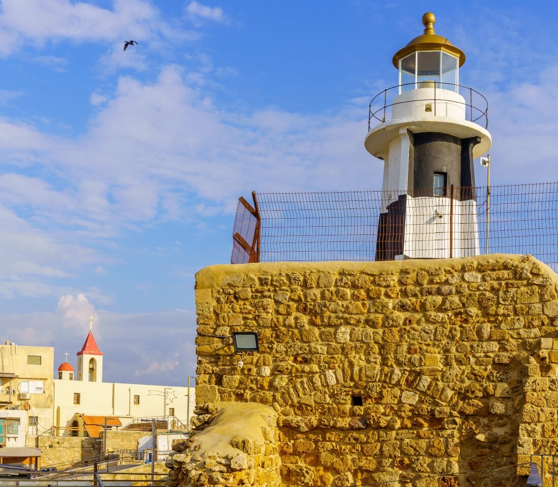 View of the lighthouse, with Saint John the Baptist church in the background, in the Old City of Akko. Photo by RnDmS via Shutterstock.com