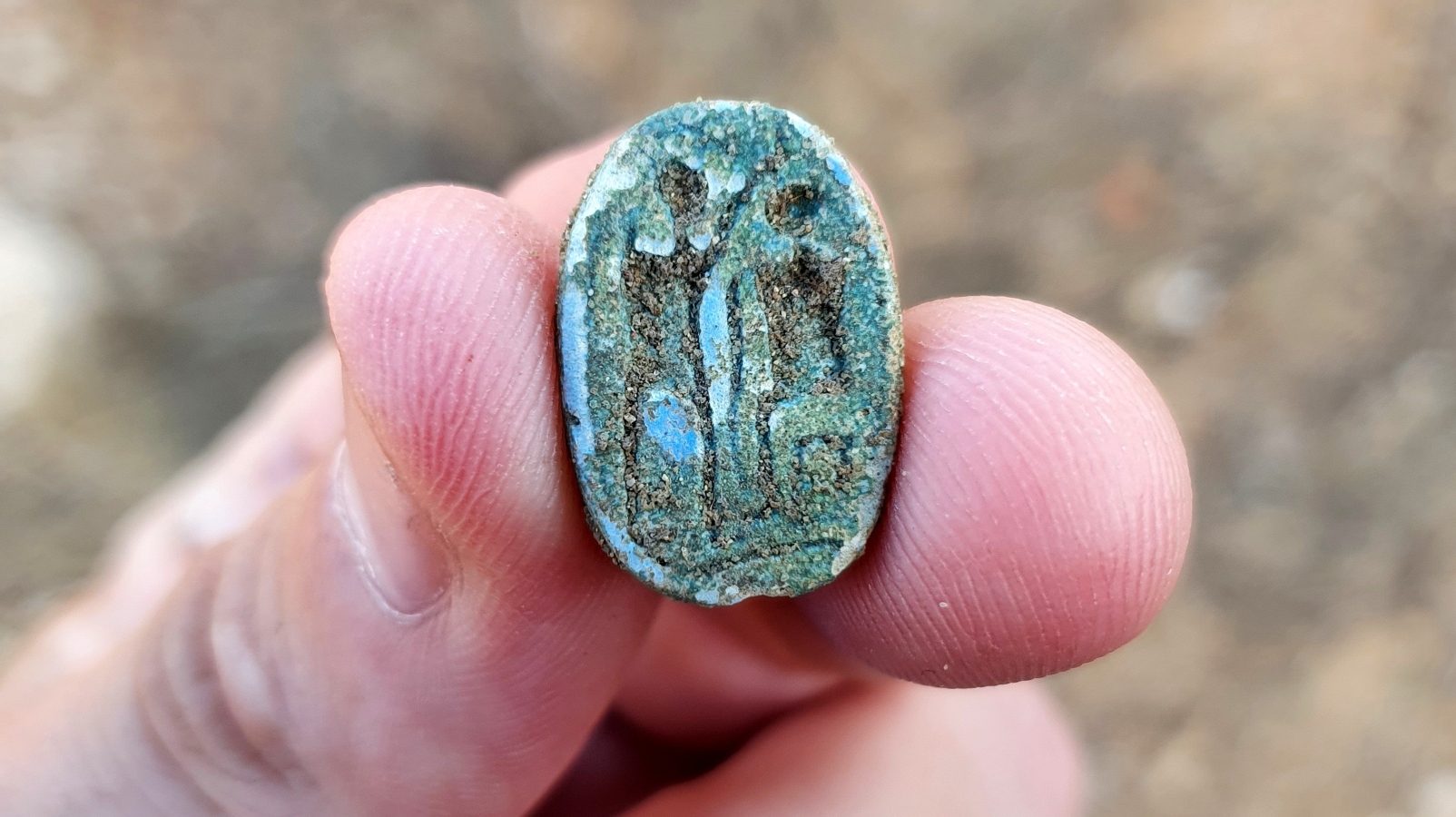 The scarab, showing a seated figure on the right and a standing figure with a raised arm on the left, possibly symbolizing the imparting of authority. Photo by Gilad Stern/Israel Antiquities Authority