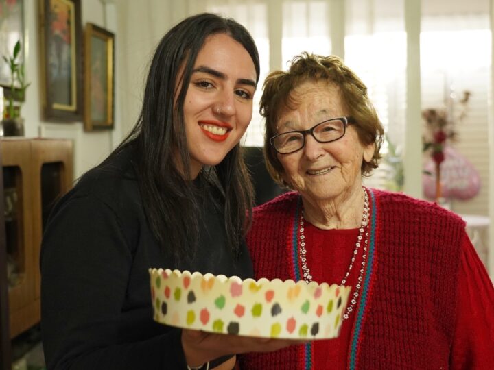 Moran Oheva, 25, a musician from Holon, presenting a home-baked cake to Holocaust survivor Elka Rabinowitz, 91, also of Holon. Photo courtesy of Uga B’Haftaha
