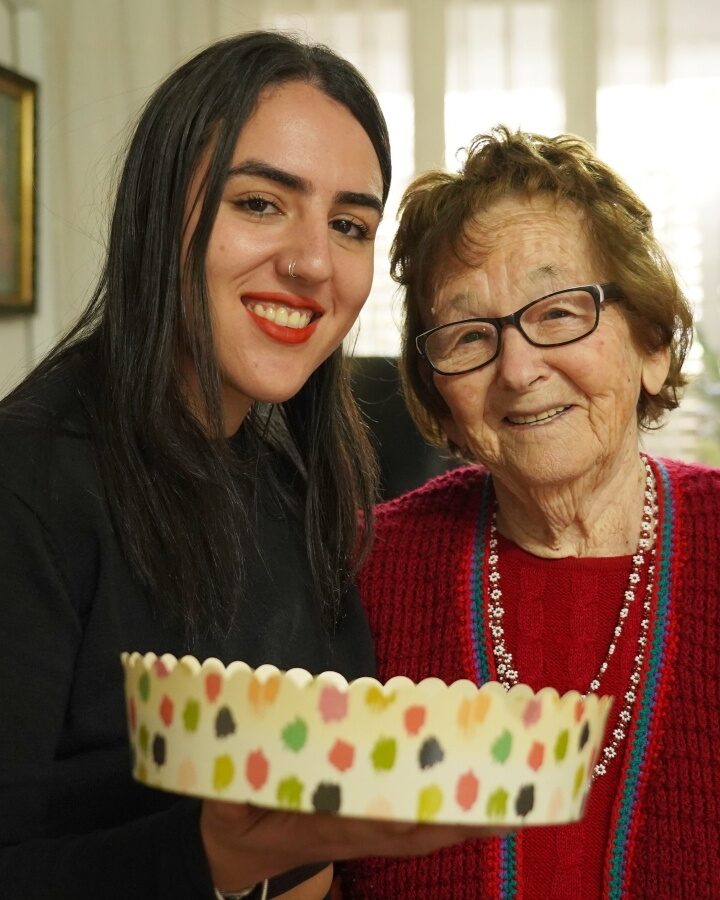 Moran Oheva, 25, a musician from Holon, presenting a home-baked cake to Holocaust survivor Elka Rabinowitz, 91, also of Holon. Photo courtesy of Uga B’Haftaha
