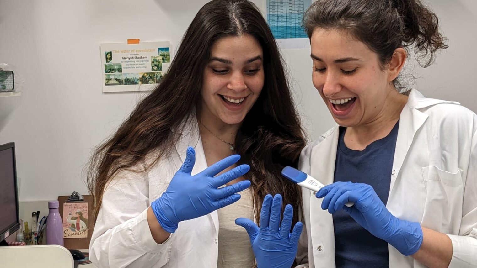 PhD student and study co-author Moran Rahamim, left, and Dr. Moriyah Naama with positive pregnancy tests they used in their experiments at Hebrew University-Hadassah Medical School. Photo by Dana Orzach