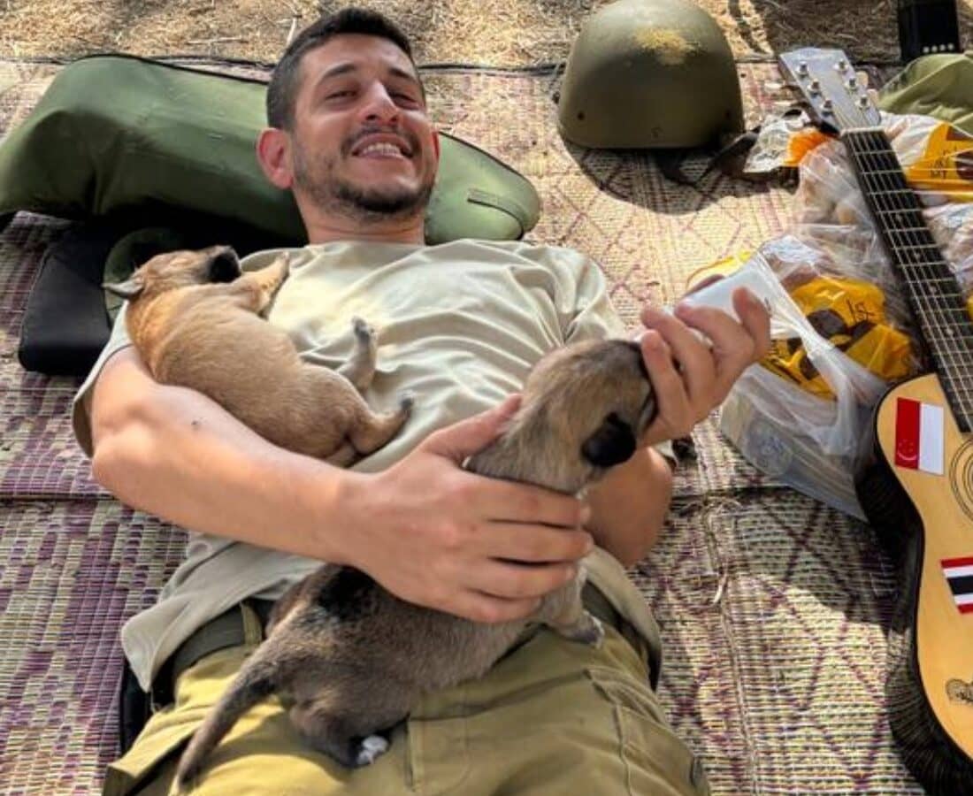 Soldier Sa’ar Berkowitz bottle-feeding abandoned puppies. Photo courtesy of Ilana Curiel