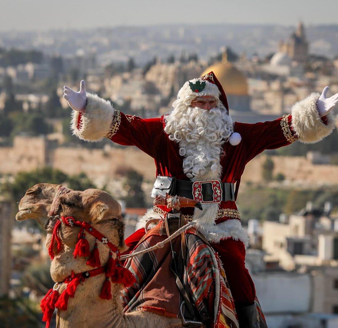 Issa Kassissieh, dressed as Santa Claus rides on a camel at Mount of Olives, overlooking the Old City of Jerusalem, ahead of the upcoming holiday of Christmas, December 4, 2023. Photo by Jamal Awad/Flash90