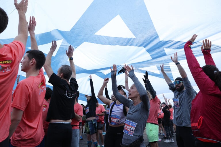 An enormous Israeli flag was hoisted by runners at the outset of the race, paying tribute to those affected by the war with Hamas. Photo by SportPhotography.