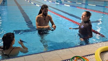 Ella Azaria, right, instructing two adults in the pool. Photo courtesy of Swimming Toward Resilience