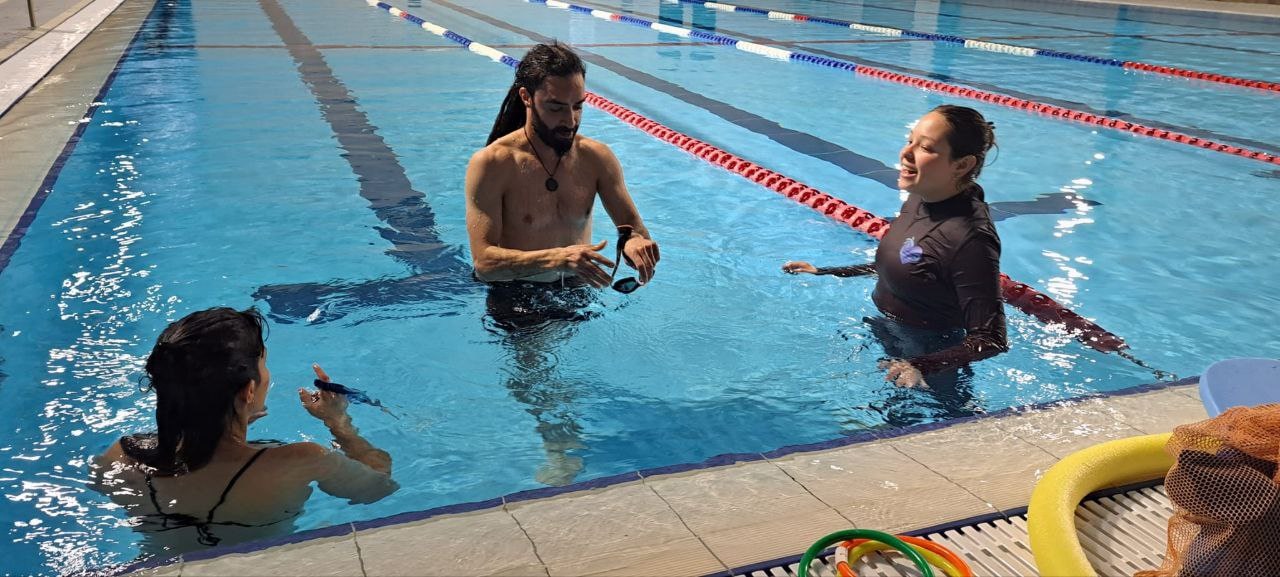 Ella Azaria, right, instructing two adults in the pool. Photo courtesy of Swimming Toward Resilience