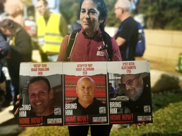 Avigail, an activist at Hostage Square in Beersheva, holding images of three captives. Photo by Yulia Karra